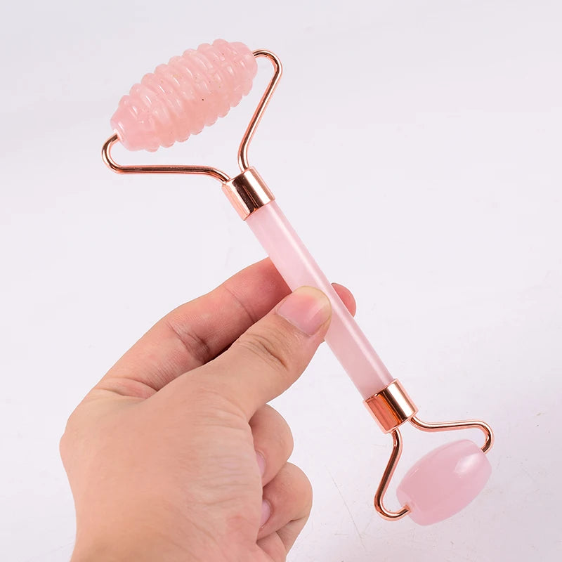 Rouleau de massage visage en quartz rose tenu en main